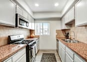 Thumbnail 9 of 25 - A kitchen with a black stove top oven and a black microwave above it.