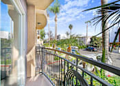 Thumbnail 6 of 25 - A balcony with a metal railing and a view of a street with cars and palm trees.