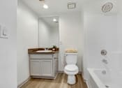 Thumbnail 24 of 25 - A white toilet sits in a bathroom next to a bathtub.