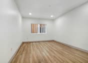 Thumbnail 22 of 25 - A room with wooden flooring and a window with blinds.