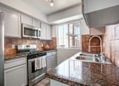 Thumbnail 2 of 25 - A kitchen with a granite counter top and stainless steel appliances.