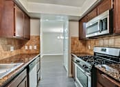 Thumbnail 10 of 25 - A kitchen with a black stove top oven and a black microwave above it.