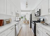 Thumbnail 6 of 20 - A kitchen with white cabinets and a black stove top oven.
