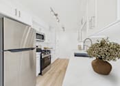Thumbnail 7 of 20 - A modern kitchen with a stainless steel refrigerator and wooden flooring.