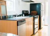Thumbnail 6 of 10 - a kitchen with wooden cabinets and a black refrigerator