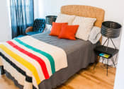 Thumbnail 7 of 10 - a bedroom with a bed with a striped comforter and orange pillows
