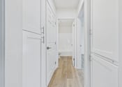 Thumbnail 18 of 74 - A long hallway with white doors and a wooden floor.