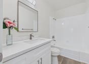 Thumbnail 19 of 74 - A white bathroom with a sink, toilet, and mirror.