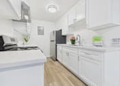 Thumbnail 11 of 74 - A white kitchen with a black fridge and a white counter.