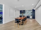 Thumbnail 8 of 27 - a dining area with a wooden table and chairs and a kitchen in the background