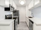 Thumbnail 19 of 24 - an empty kitchen with white cabinets and stainless steel appliances