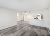 Thumbnail 21 of 24 - the living room and kitchen of an apartment with white walls and wood flooring