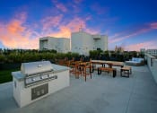 Thumbnail 32 of 39 - a rooftop patio with a grill and tables and a city in the background