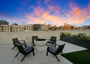 Thumbnail 29 of 39 - a rooftop patio with chairs and a fire pit with the city skyline in the background