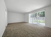 Thumbnail 1 of 16 - Living room in 1-bedroom at Ashton Pointe with carpeted floors and sliding glass door that opens to a private patio.