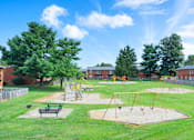 Thumbnail 12 of 17 - Apartment playground and picnic area at Mount Vernon, featuring play equipment, benches, and open space for outdoor activities.