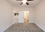 Thumbnail 24 of 27 - A room with a ceiling fan and carpeted floor.