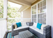 Thumbnail 13 of 27 - A patio with a white couch and a glass table.
