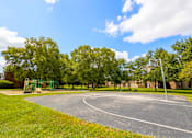 Thumbnail 11 of 24 - Basketball court at Briarwood Apartments, Columbus, IN, with hoops and a paved playing surface.