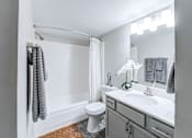 Thumbnail 16 of 39 - Bathroom with vanity and a full size bathtub with tile surround at Woods of Fairfax.