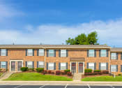 Thumbnail 12 of 13 - Exterior view of Carriage House Apartments in New Albany, showcasing the building's architecture and adjacent parking area for residents.