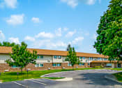 Thumbnail 13 of 15 - Exterior view of a building at Wesley Park Apartments with a parking lot in front.