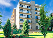 Thumbnail 3 of 9 - Exterior view of Village Square Apartments showcasing the building's design and landscape.