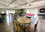 Thumbnail 10 of 63 - Interior of the clubhouse at Woodbridge Apartments in Bloomington, featuring furniture, pool table, and seating areas.