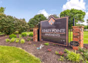 Thumbnail 20 of 21 - Community entrance at Ashley Pointe Apartments with brick sign and flower beds.