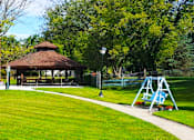 Thumbnail 11 of 13 - A gazebo sits in a park with a playground in the foreground.