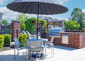 Thumbnail 10 of 27 - A patio with a table and chairs under an umbrella.