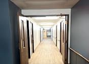 Thumbnail 14 of 17 - A long hallway with doors on each side at Kentwood Square Apartments.