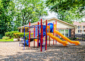 Thumbnail 6 of 9 - A playground with a red and yellow slide in front of a building.