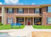 Thumbnail 8 of 9 - A brick building with a blue bench in front.