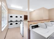 Thumbnail 2 of 13 - Laundry room at Carriage House Apartments in New Albany, featuring washers and dryers.