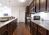 Thumbnail 2 of 27 - A kitchen with dark wood cabinets and granite countertops.