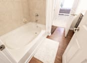 Thumbnail 20 of 27 - A white bathroom with a tub and a rug on the floor.