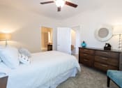 Thumbnail 18 of 27 - A bedroom with a bed, dresser, and ceiling fan.