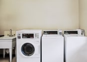 Thumbnail 8 of 16 - On-site clothes care center at Cambridge Square Apartments in Greenwood, featuring washers and dryers.