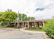 Thumbnail 2 of 15 - A building with a flag on top and a yellow sign on the front.