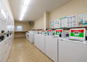 Thumbnail 9 of 15 - A laundromat with washers and dryers lined up and instructions on the wall.