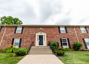 Thumbnail 11 of 15 - A red brick building with a black door and windows.