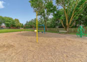 Thumbnail 7 of 21 - Playground at Ashley Pointe Apartments with swing sets, tetherball and climbing equipment
