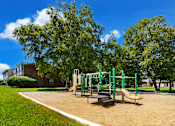Thumbnail 10 of 24 - Playground at Briarwood Apartments, Columbus, IN, with swings, slides, and green space.