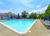 Thumbnail 34 of 39 - Swimming pool at Woods of Fairfax, featuring clear water and surrounding lounge chairs.