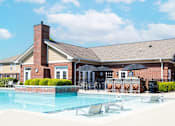 Thumbnail 9 of 27 - A pool in front of a brick house with a black umbrella.