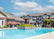 Thumbnail 1 of 27 - A swimming pool in front of apartment buildings.