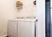 Thumbnail 14 of 27 - A white washing machine and dryer in a small laundry room.