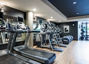Thumbnail 23 of 37 - Fitness center with cardio machines and free weights at The Lyric Apartments, Washington