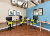 Thumbnail 7 of 29 - A room with a blue wall and a desk with two chairs.